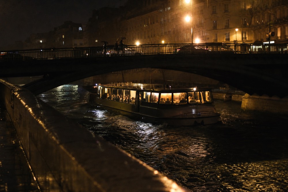Large Bateaux Mouches boat lit up at night on the Seine with passengers seated for dinner, no text, no logos, no people