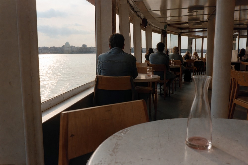Guests in denim and casual jackets seated at a dinner table on a Seine cruise boat, no text, no logos, no people.