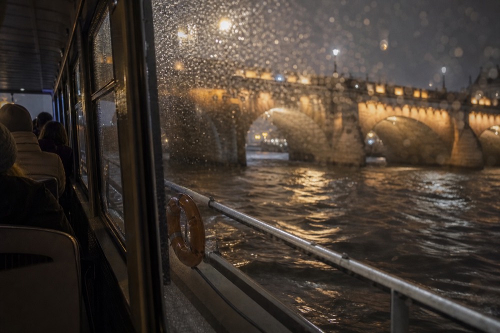 A Seine dinner cruise boat passing lit bridges on the river at night, no text, no logos, no people.