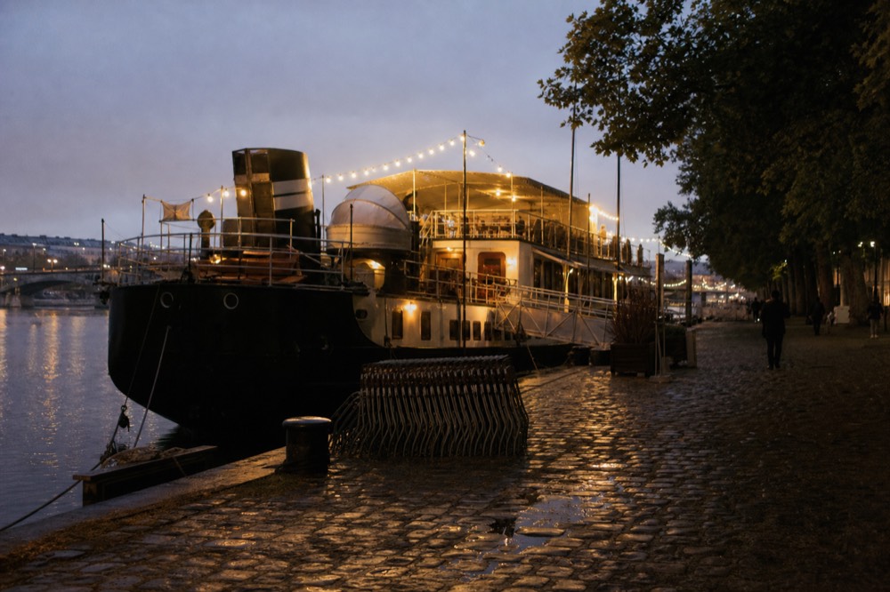 A river boat lit for the evening moored on the Seine in Paris, no text, no logos, no people