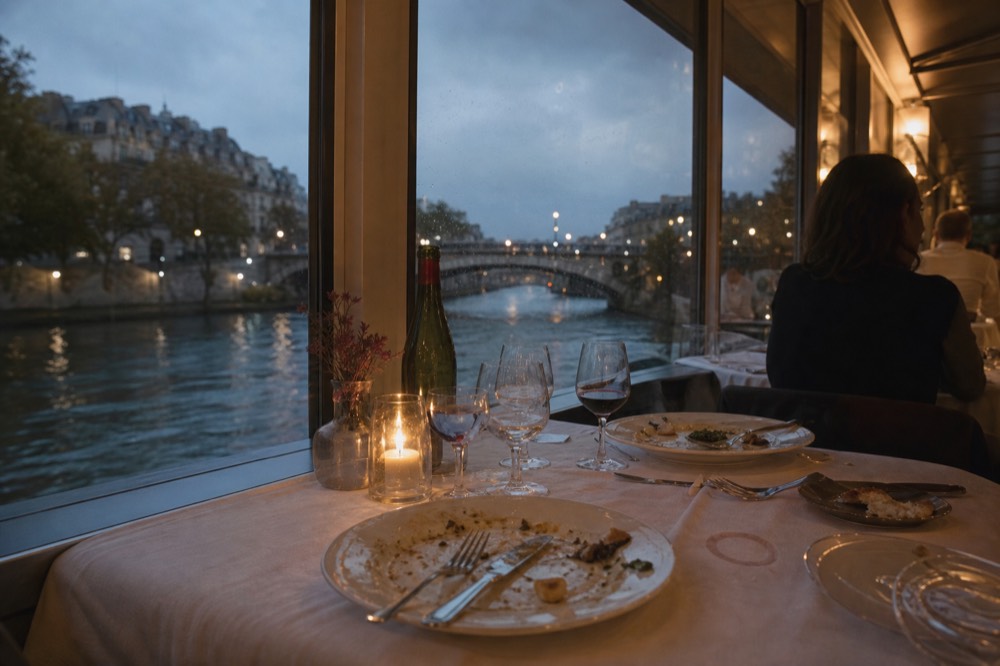 Candlelit dinner table aboard a river boat on the Seine, no text, no logos, no people