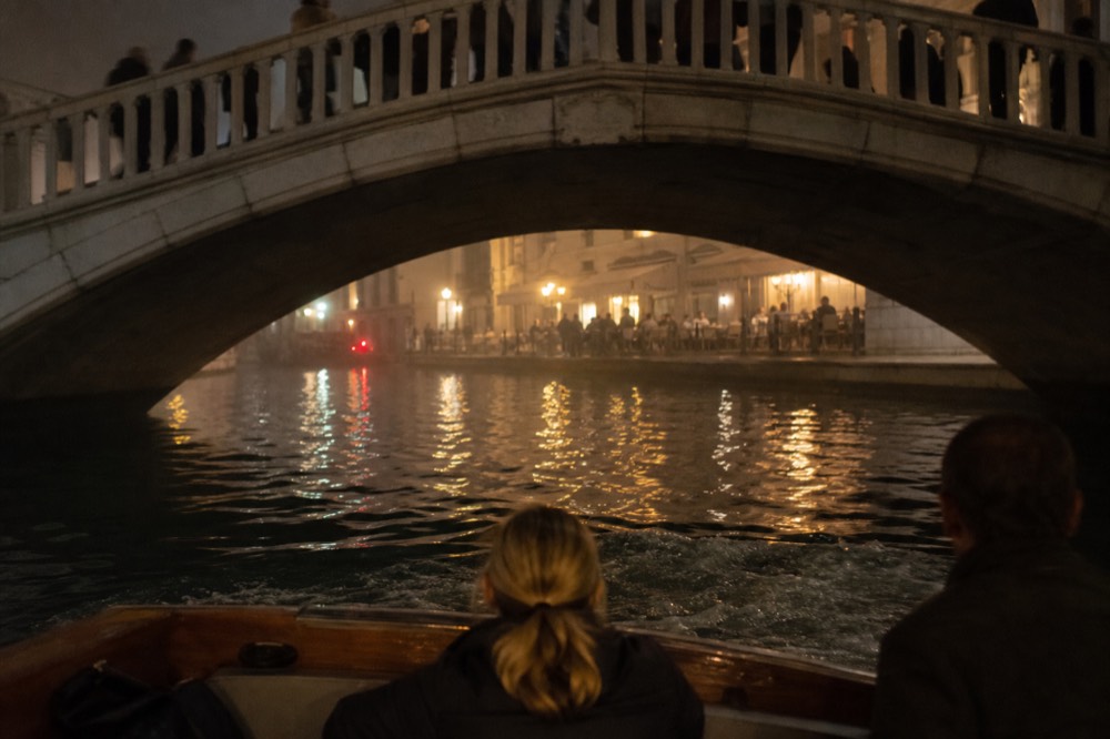 Dinner cruise boat gliding past illuminated Parisian bridges on the Seine at night, no text, no logos, no people