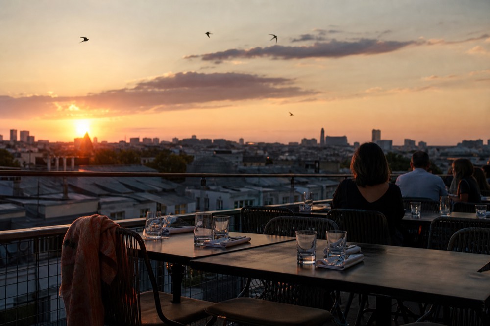 Cruise boat deck with diners' place settings and the Paris skyline glowing at dusk, no text, no logos, no people