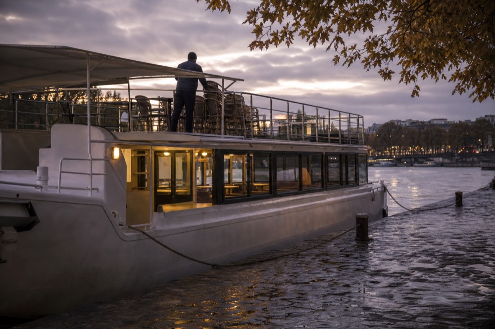 Seine cruise boat moored at a lit Paris quay in the evening, no text, no logos, no people