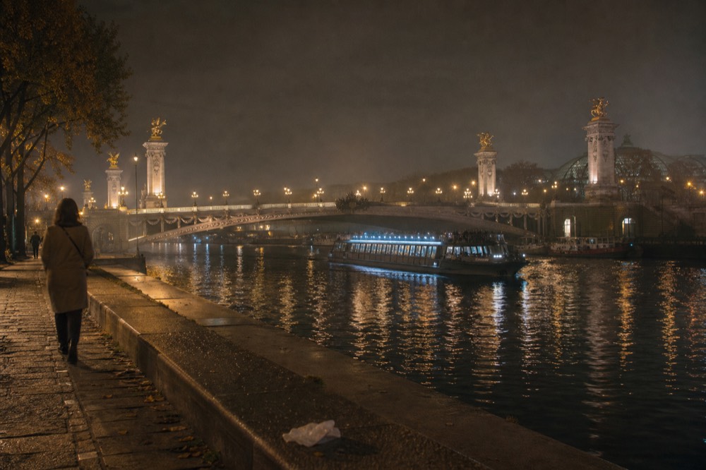 Wide view of the Seine at night with lit bridges and a cruise boat, no text, no logos, no people
