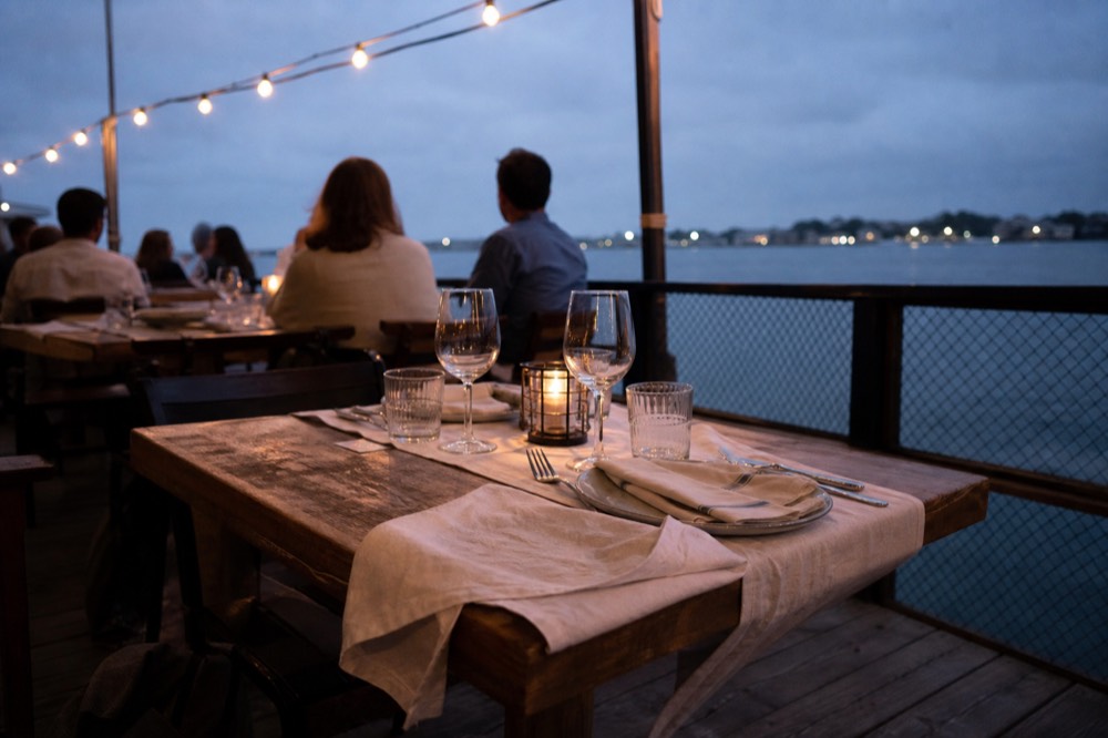 Smart-casual dinner setting on a covered Seine cruise deck in the evening, no text, no logos, no people