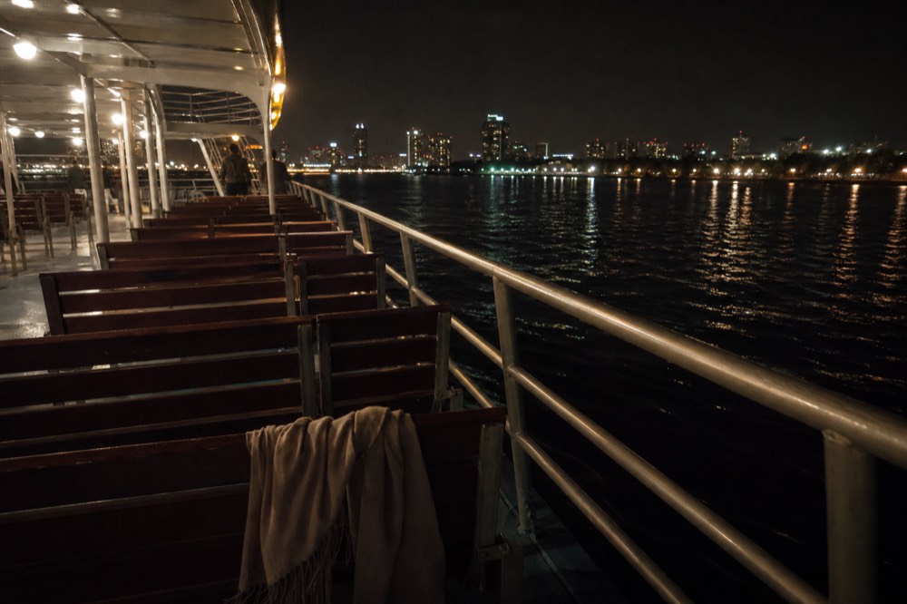 Open deck of a Seine cruise boat at night with city lights reflecting on the water, no text, no logos, no people