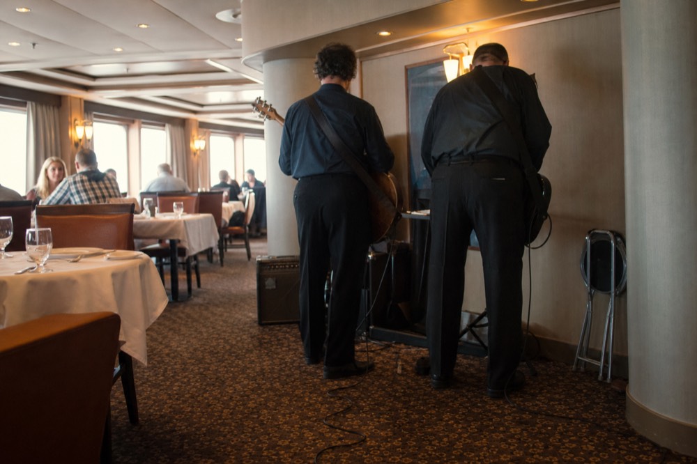 White-tablecloth dining room on a Seine cruise with musicians setting up, no text, no logos, no people