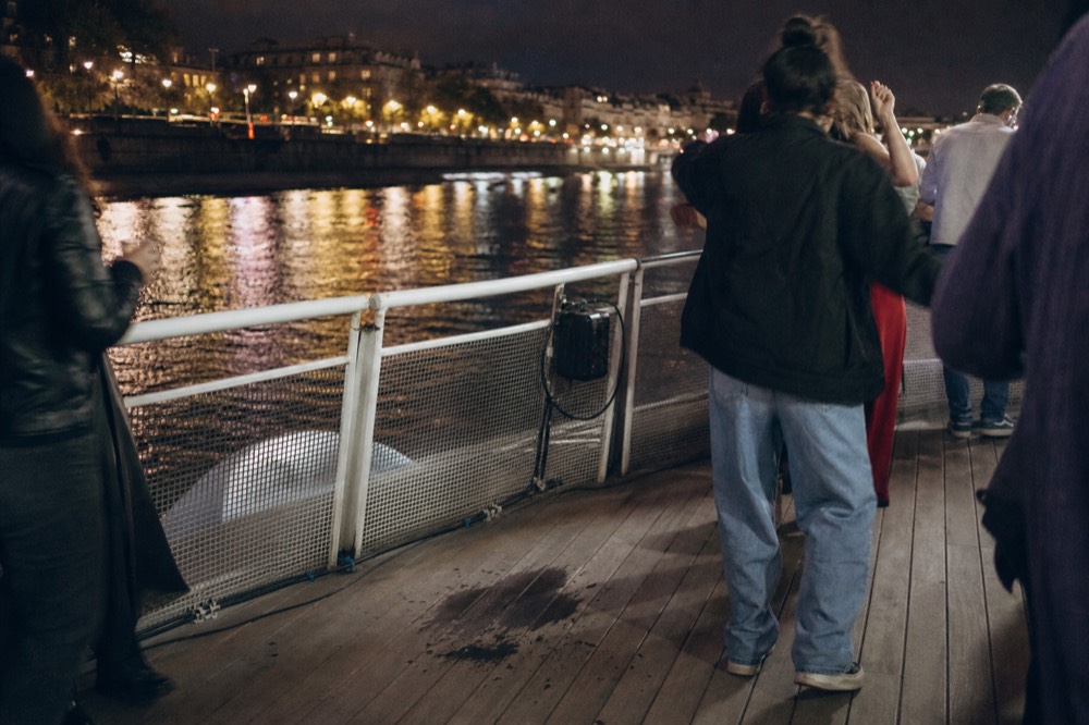 Evening party atmosphere on a dinner cruise deck with city lights reflected on the Seine, no text, no logos, no people