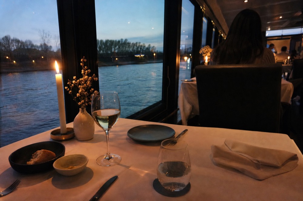 An elegant candlelit dining table set with fine glassware aboard a modern river boat, no text, no logos, no people