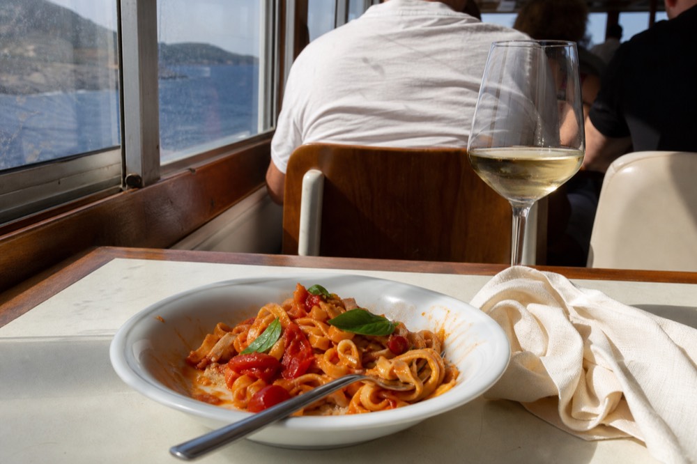 A serving of fresh pasta with tomato and basil on a restaurant plate, no text, no logos, no people