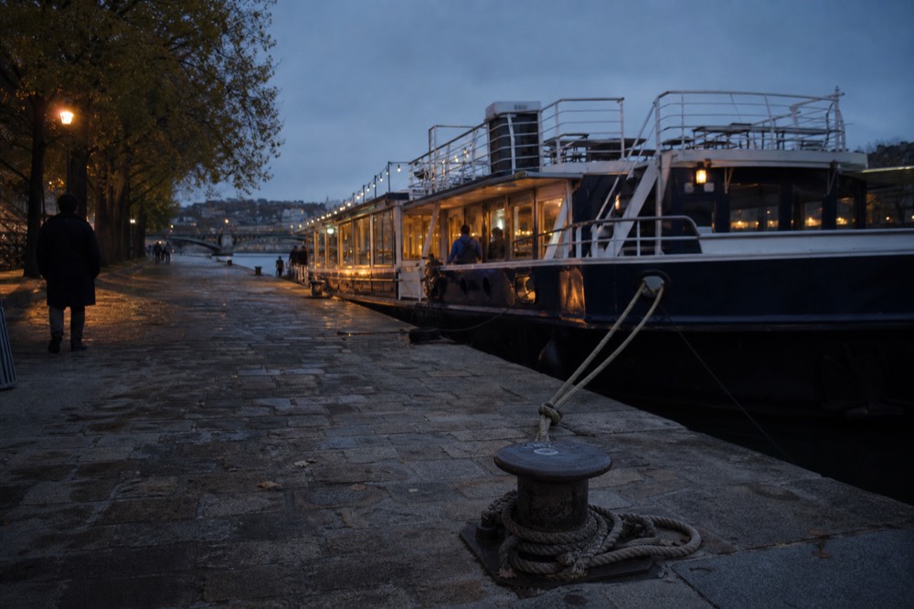 A Seine riverside quay at dusk with a boarding pier and moored boats, no text, no logos, no people