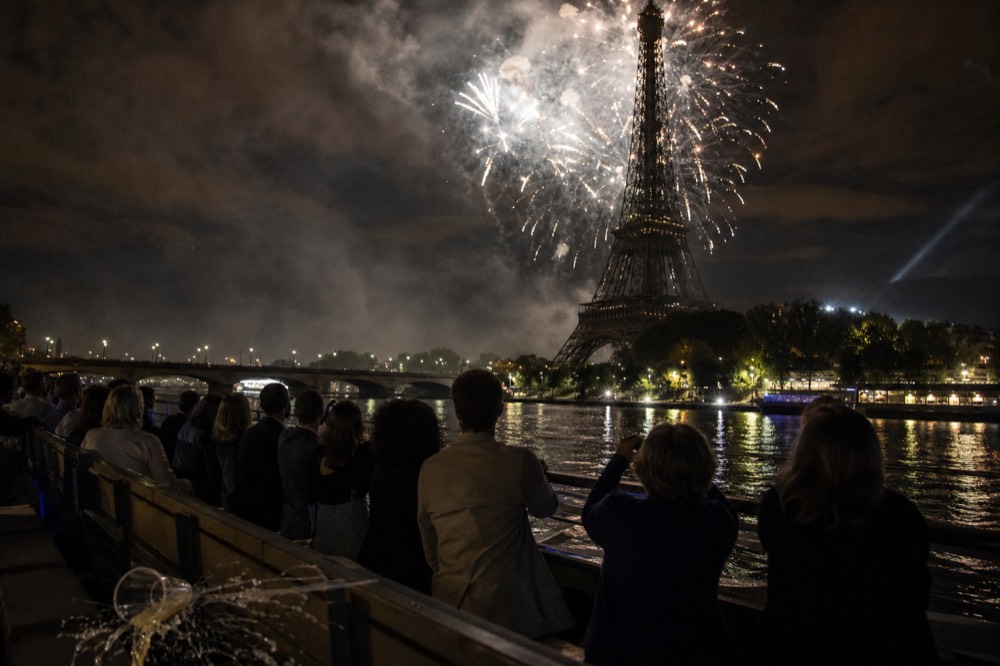 Fireworks bursting over the Eiffel Tower as seen from the Seine, no text, no logos, no people