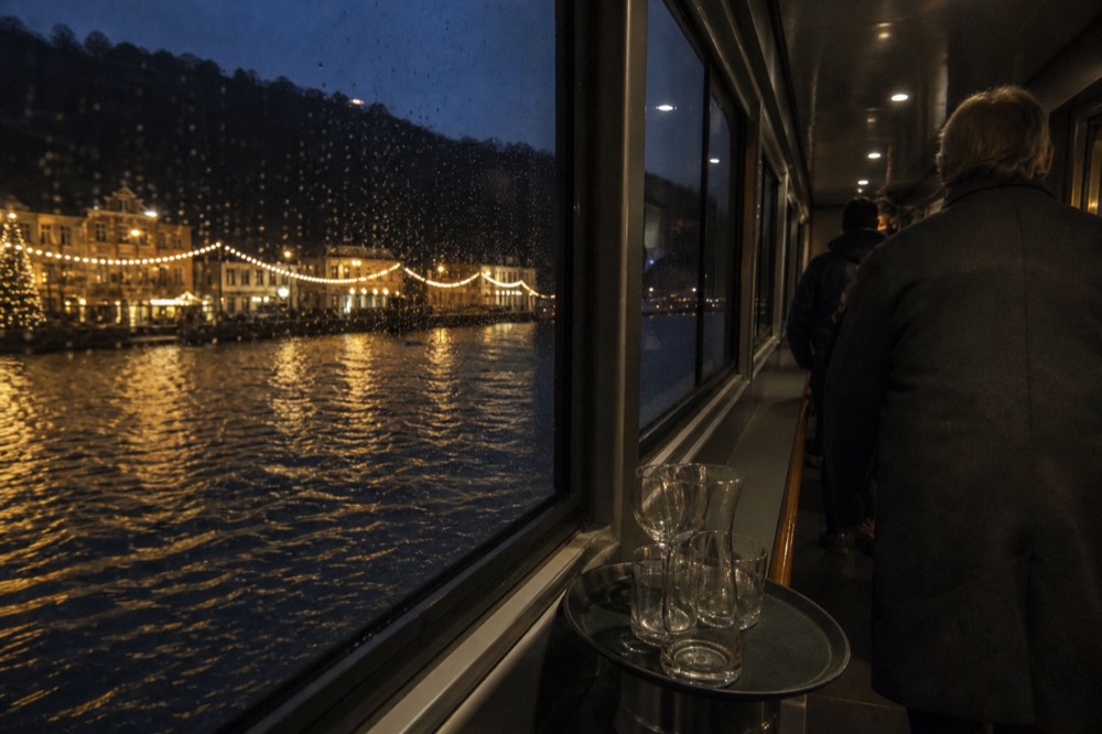 A dinner cruise boat passing Paris Christmas lights along the Seine at night, no text, no logos, no people