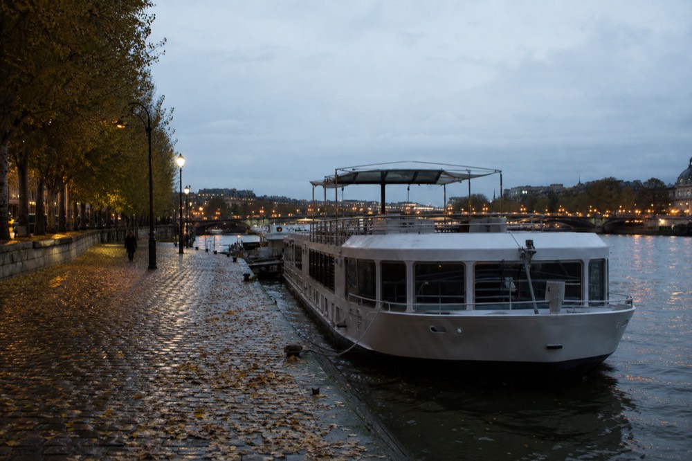 Seine riverbank with lamp posts and moored cruise boat in soft evening light, no text, no logos, no people