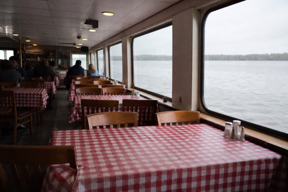 A casual bistro-style dining room on a Seine cruise boat with set tables, no text, no logos, no people.