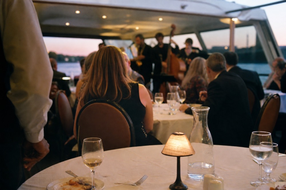 A white-tablecloth dinner setting with a jazz band in the background on a Seine dinner cruise, no text, no logos, no people